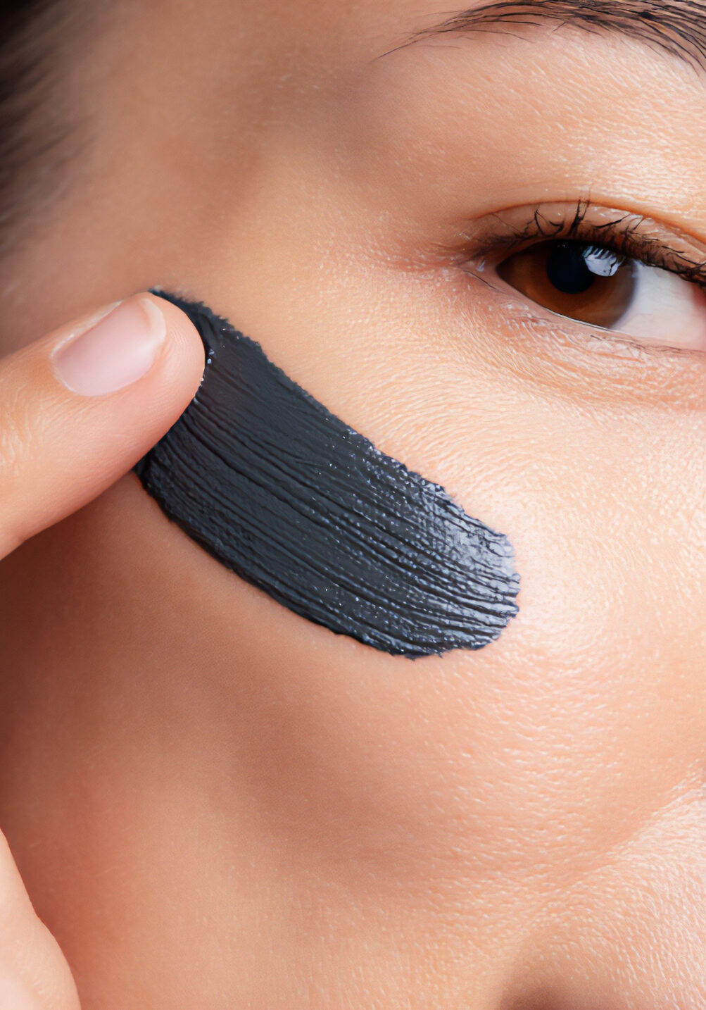 hand applying charcoal clay mask to face